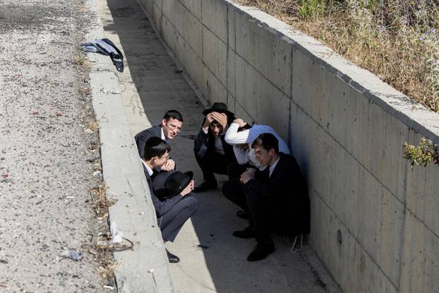 Israelis take shelter at the side of a highway as siren sounds following missile attack from Iran on Israel, in central Israel
