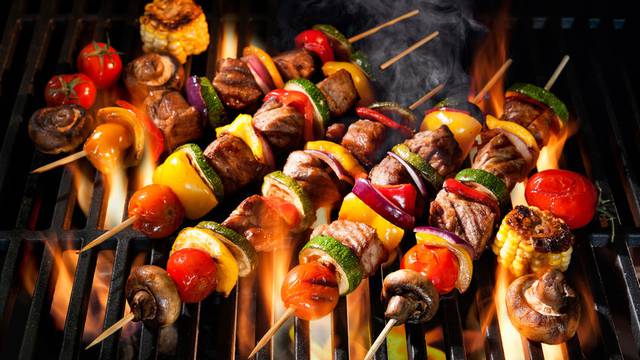 Meat kebabs with vegetables on flaming grill