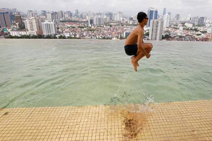 A boy jumps into the water at the gold-plated infinity pool of the newly inaugurated Dolce Hanoi Golden Lake luxury hotel in Hanoi