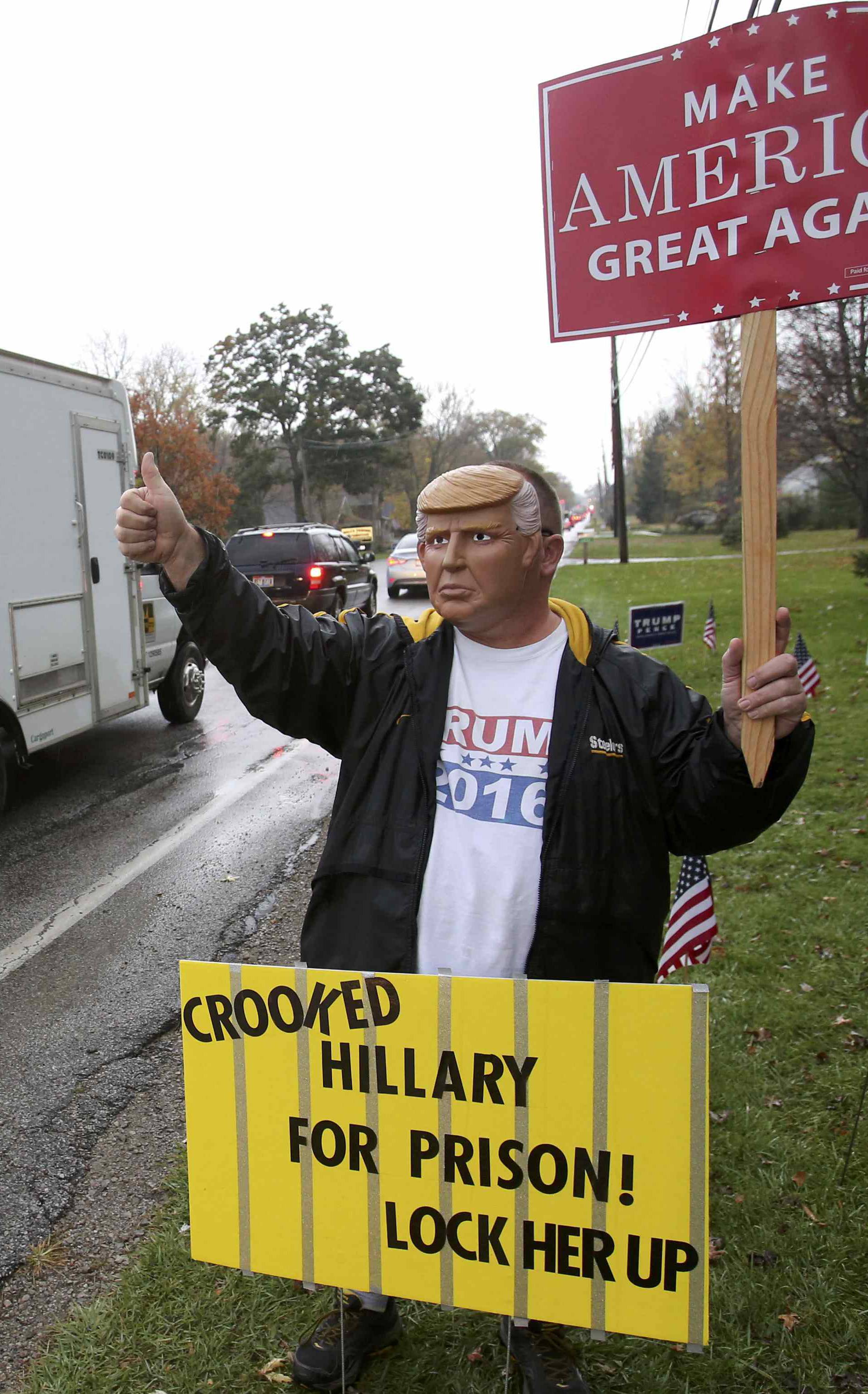 Robert Stottlemire waves to cars as they pass by while wearing a Donald Trump mask during the U.S. presidential election in Ohio