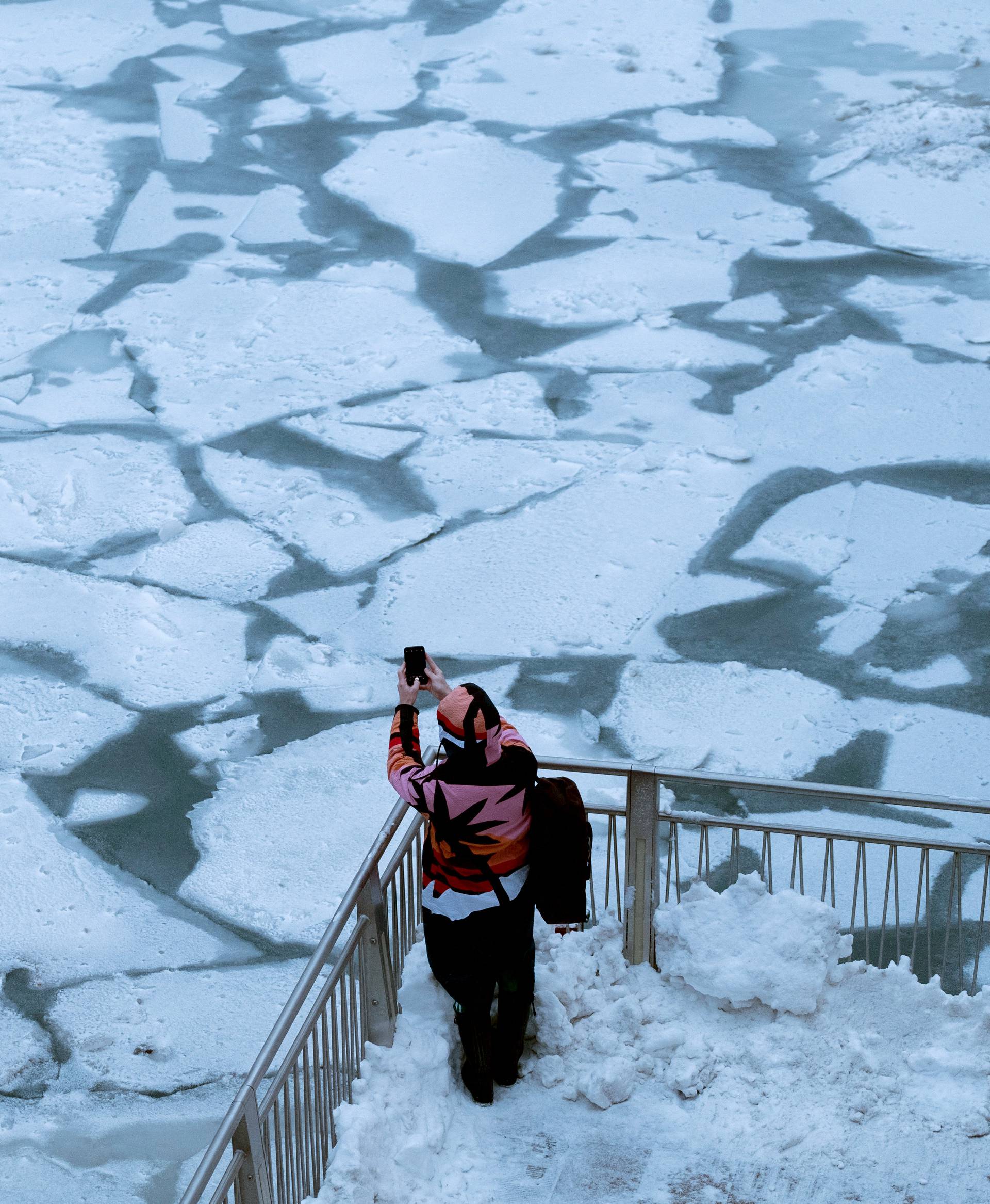 A pedestrian stops to take a photo by Chicago River as bitter cold phenomenon called the polar vortex has descended on much of the central and eastern United States