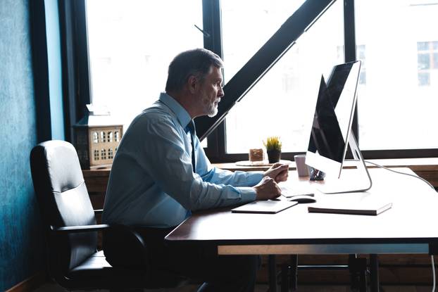 Mature Businessman Working On Computer In Office