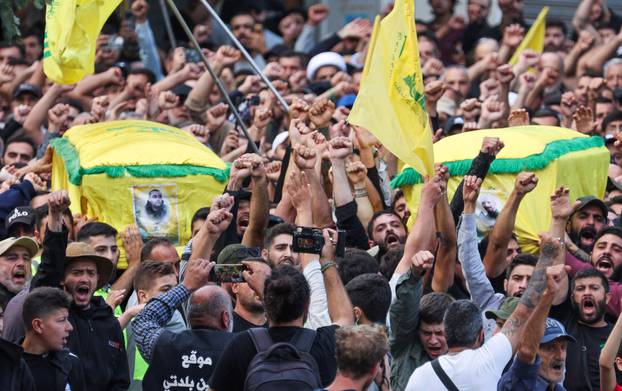 People gesture during the funeral of Hezbollah members Ali Ftouni and Hussam Ibrahim, who died during Israeli shelling on south Lebanon yesterday, in Khirbit Silm