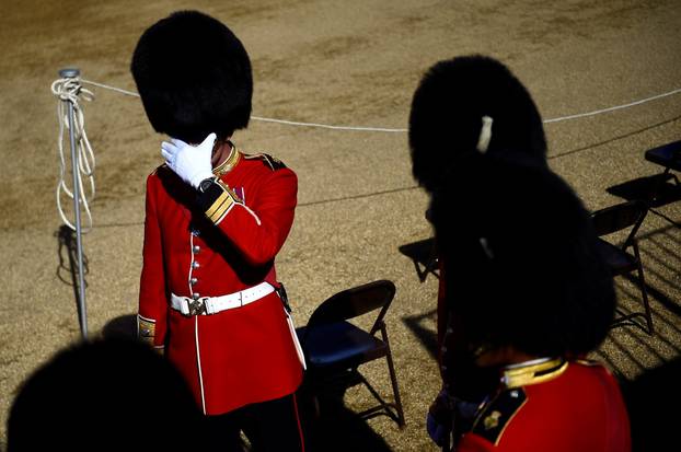 A guard member shields his eyes from the sun before the Household Division rehearse Trooping the Colour for the Colonel