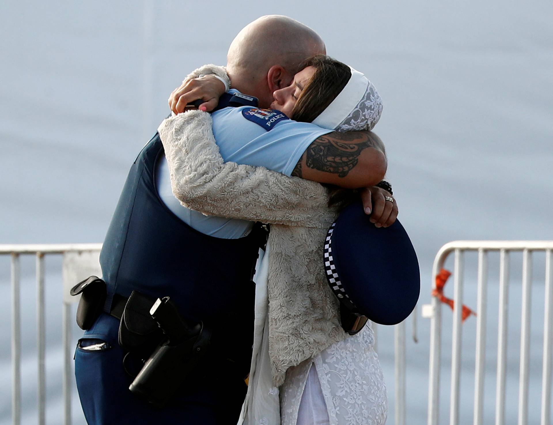 A relative of a victim of the mosque attacks hugs a policeman during a mass burial at Memorial Park Cemetery in Christchurch