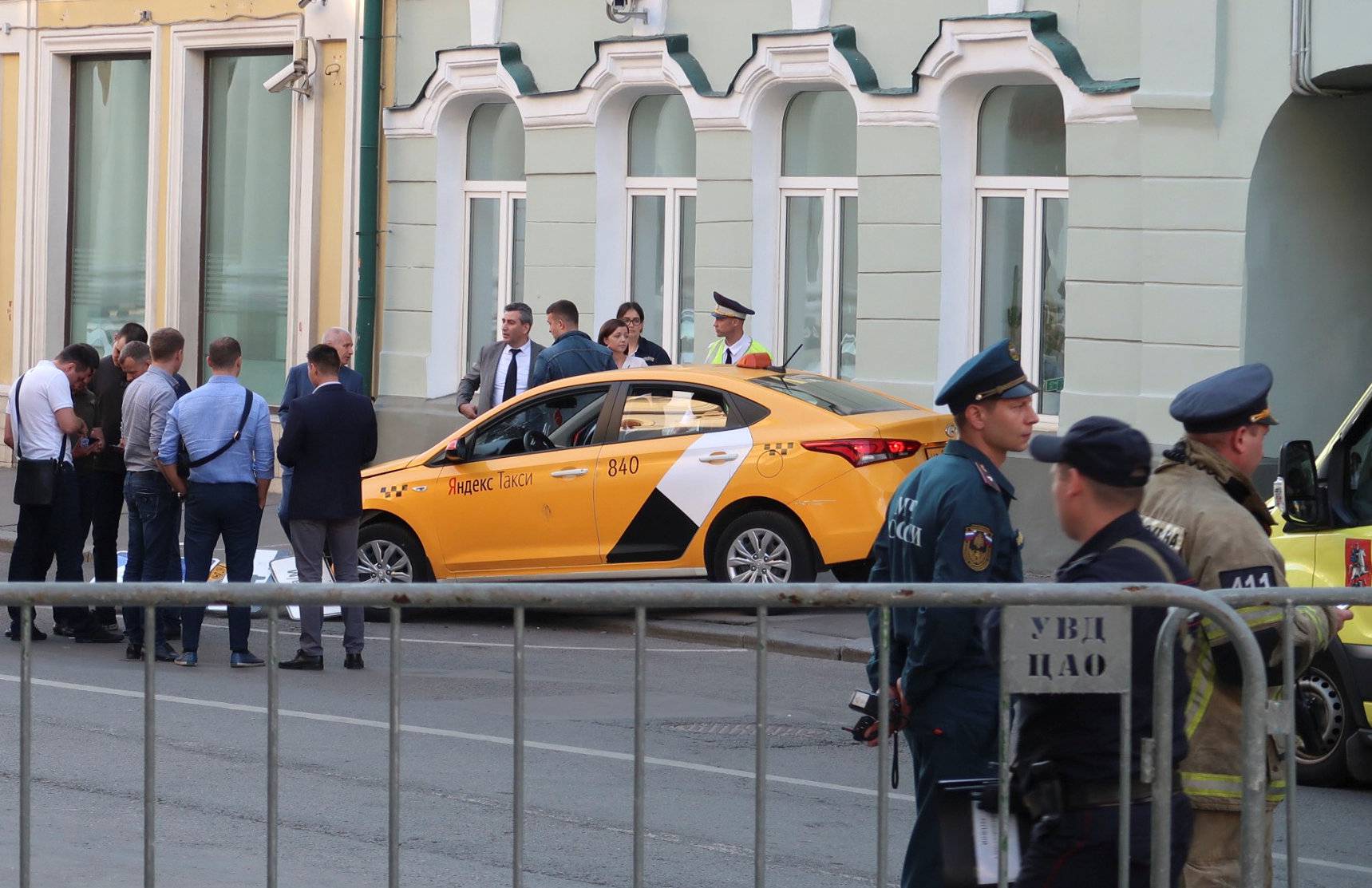 Investigators and members of emergencies services gather near a damaged taxi, which ran into a crowd of people, is evacuated in central Moscow