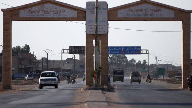 Vehicles drive along the entrance of the town of Tal Tamer