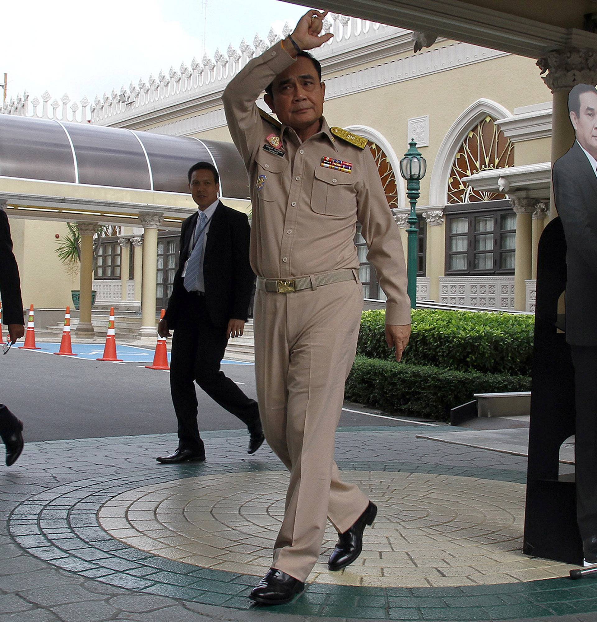 Thailand's Prime Minster Prayuth Chan-ocha speaks to reporters next to a cardboard cut-out of himself at the government house in Bangkok