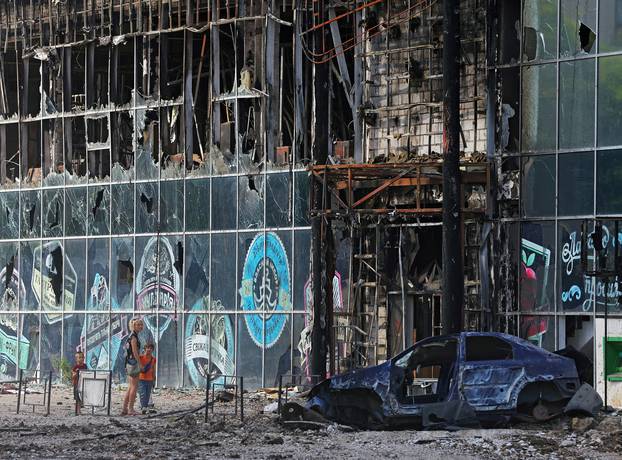 Local residents stand next to a destroyed building in Lysychansk