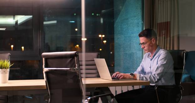 man working on laptop in dark office