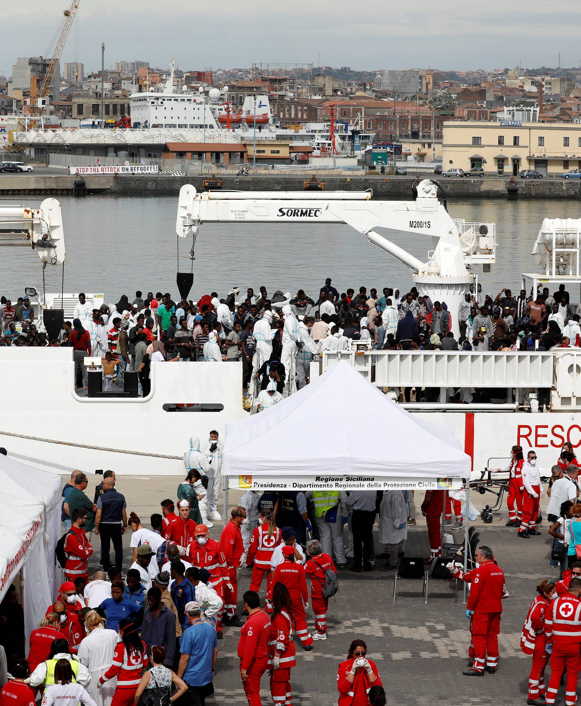 Migrants disembark Italian coast guard vessel "Diciotti" as they arrive at the port of Catania