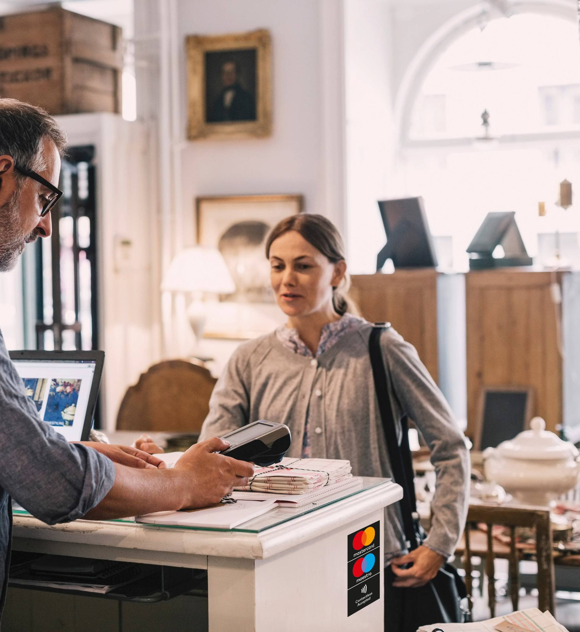 Owner using card reader in front of female customer at shop counter