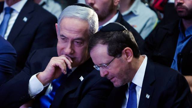 Israeli Prime Minister Benjamin Netanyahu and Israeli President Isaac Herzog speak as they attend a memorial ceremony for Israeli soldiers killed in the 1973 Middle East War at Mount Herzl Military Cemetery in Jerusalem