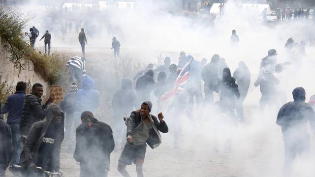 Tear gas fills the air as French riot police face off with demonstrators near the area called the "jungle" where migrants live in Calais