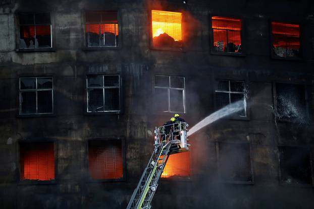 Firefighters work at the scene of a fire on the outskirts of Dhaka