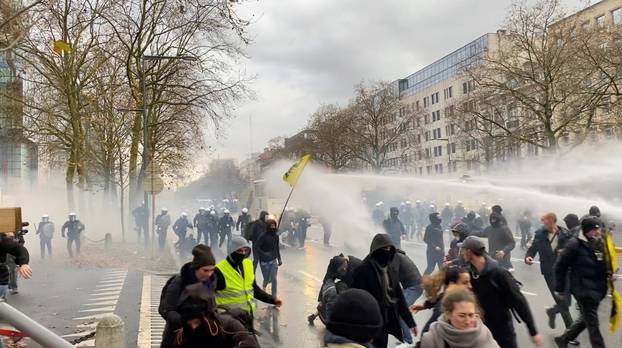 Demonstrators run away from water cannons during a protest, in Brussels