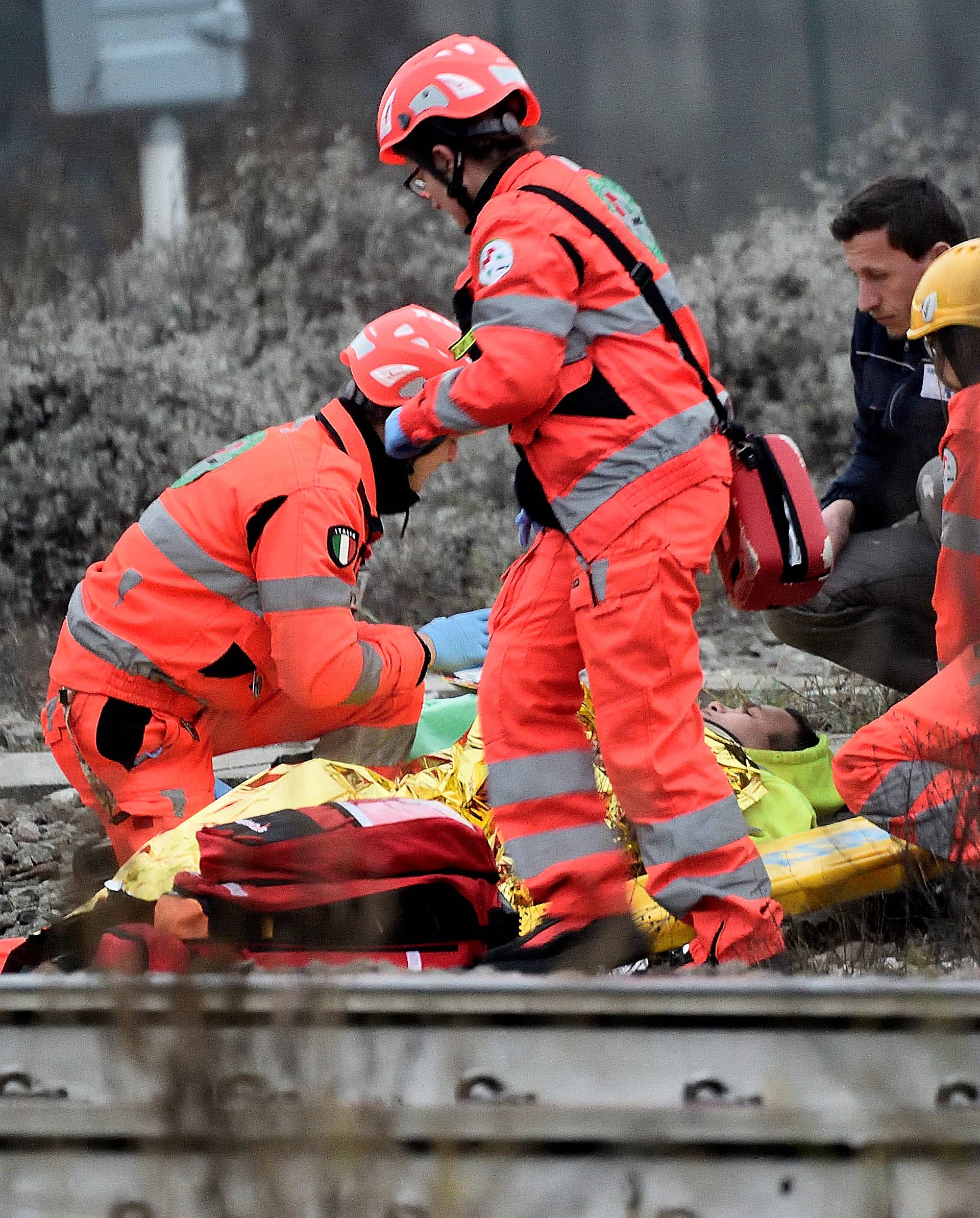 Rescue workers help an injured person on a stretcher after two trains derailed in Pioltello, on the outskirts of Milan