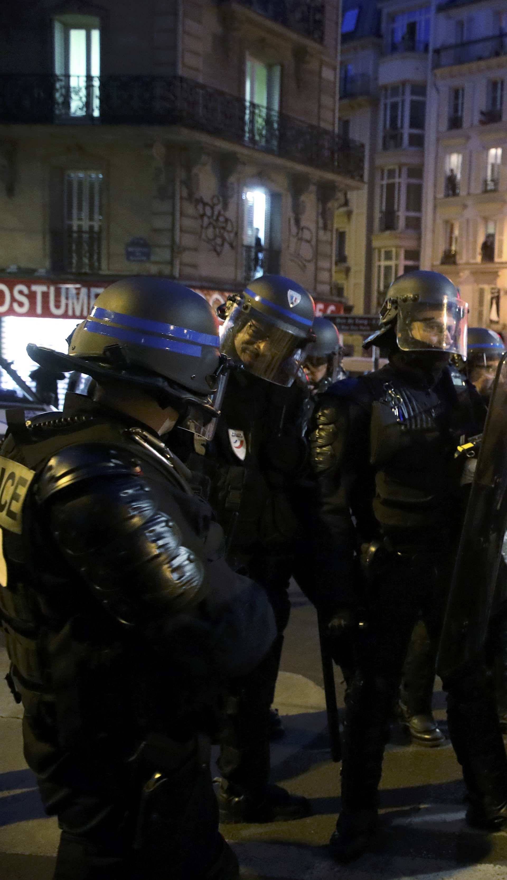 French riot police face off with people holding a banner with the message that reads, "Cops Rapists Murderers" to protest police brutality as they gather at a deomostration in Paris 