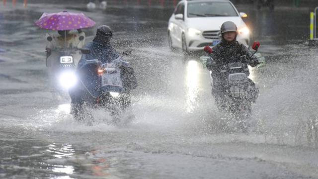 GUANGZHOU, CHINA - APRIL 20: People ride on a waterlogged road in rain on April 20, 2024 in Guangzhou, Guangdong Provinc