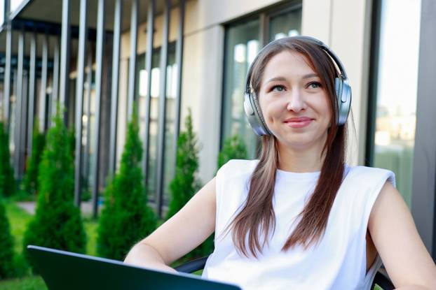 young woman wearing headphones works laptop outdoors Perfect for remote work