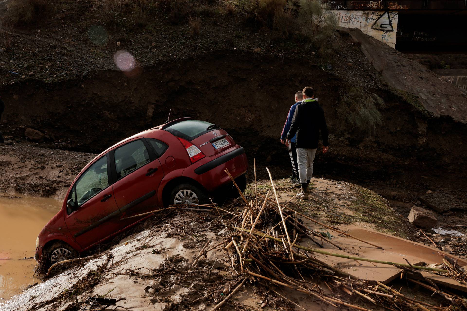 Men walk along a flooded area after heavy rains and floods in Alora