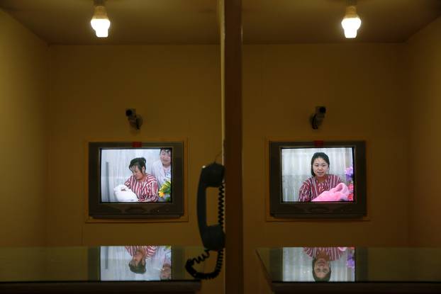 Women hold babies on screens in video conference booths built to protect mothers and babies from potential germs visitors may be bringing, at the Pyongyang Maternity Hospital visited by foreign reporters on a government organised tour in Pyongyang