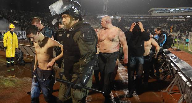 Police escort the soccer fans injured during the fights at a match between Red Star and Partizan in Belgrade