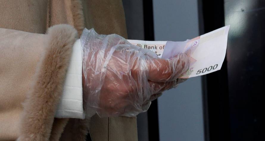 A woman wearing a plastic glove holds money as she stands in a queue to buy face masks amid the rise in confirmed cases of the novel coronavirus in Daegu