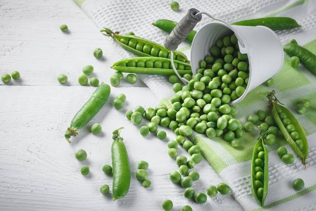 Delicious ripe green peas lying on a wooden table.