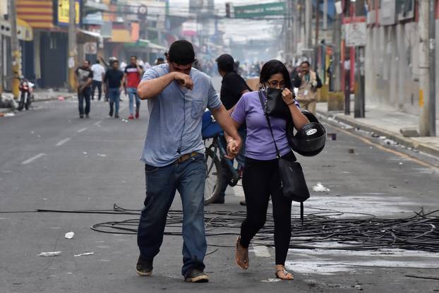 People overcome by tear gas walk away from clashes between supporters of Nasralla and police during a protest caused by the delayed vote count for the presidential election in San Pedro Sula