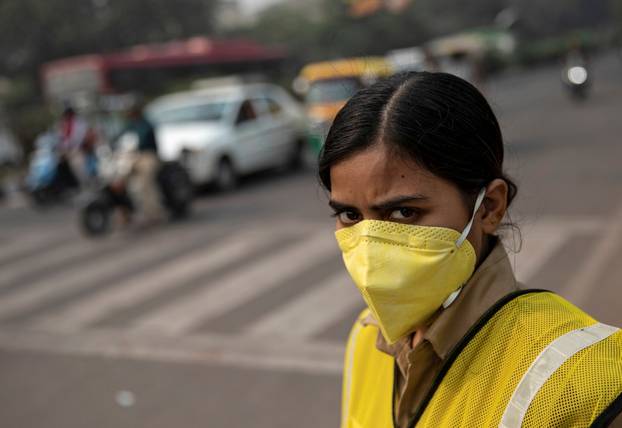 A policewoman wears a mask to protect herself from air pollution at a junction during restrictions on private vehicles based on registration plates on a smoggy morning in New Delhi