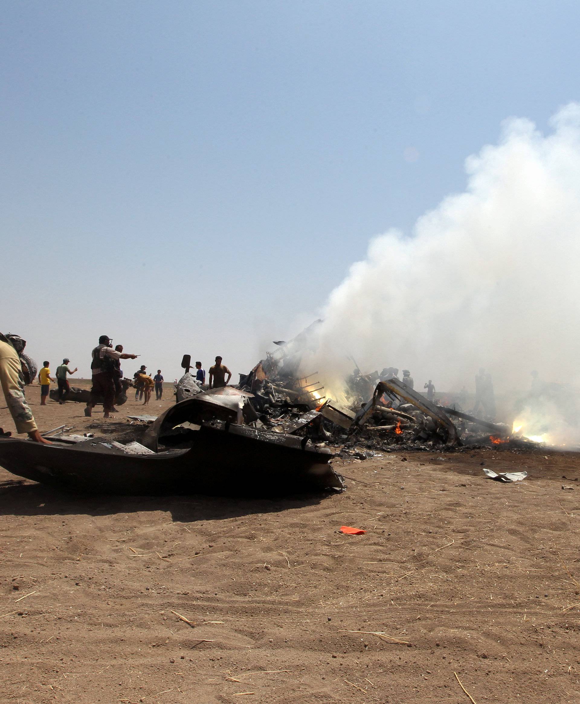 Rebel fighters and civilians inspect the wreckage of a Russian helicopter that had been shot down in the north of Syria's rebel-held Idlib province