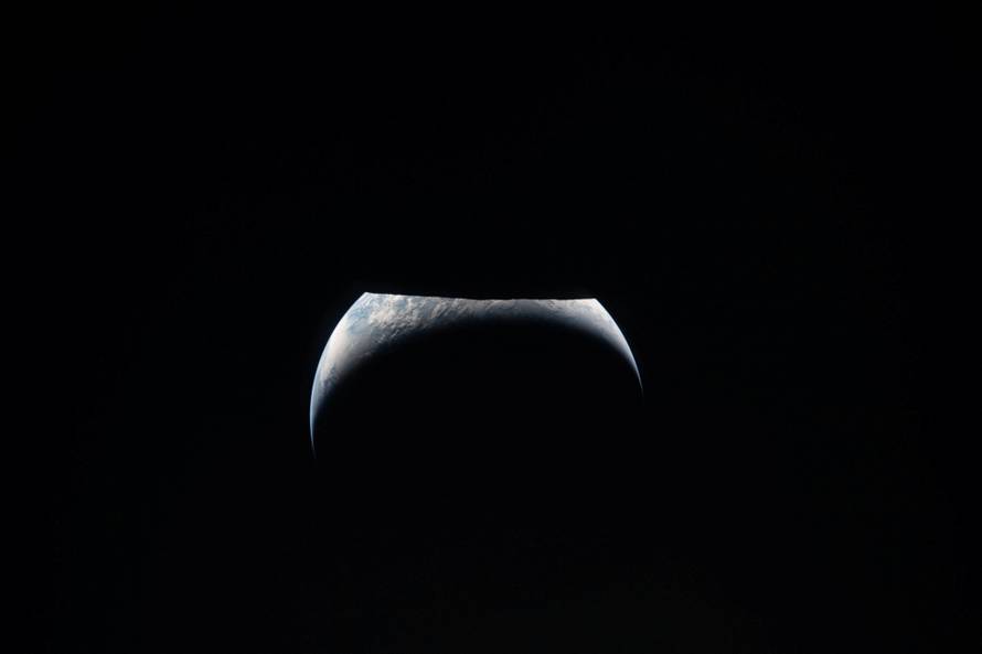 A view of Earth, partially hidden by the Moon, photographed through the Orion spacecraft window