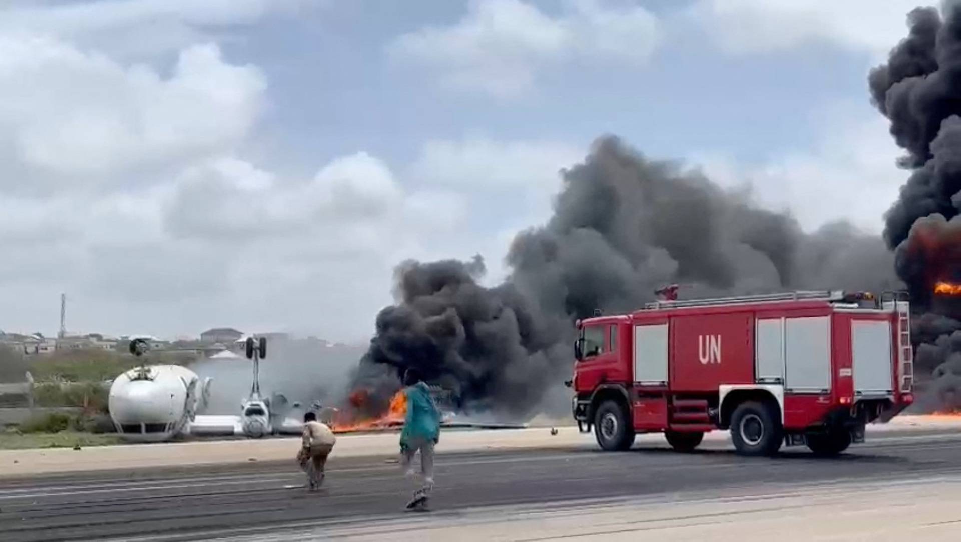 Smoke billows from a plane that flipped over after a crash landing, in Mogadishu