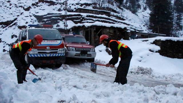 Rescue workers clear a snow-covered road to make way for an ambulance to reach the areas affected by heavy snowfall and avalanches, in Neelum Valley