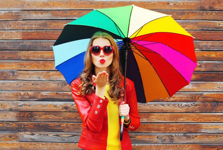 Fashion pretty woman with colorful umbrella sends air sweet kiss