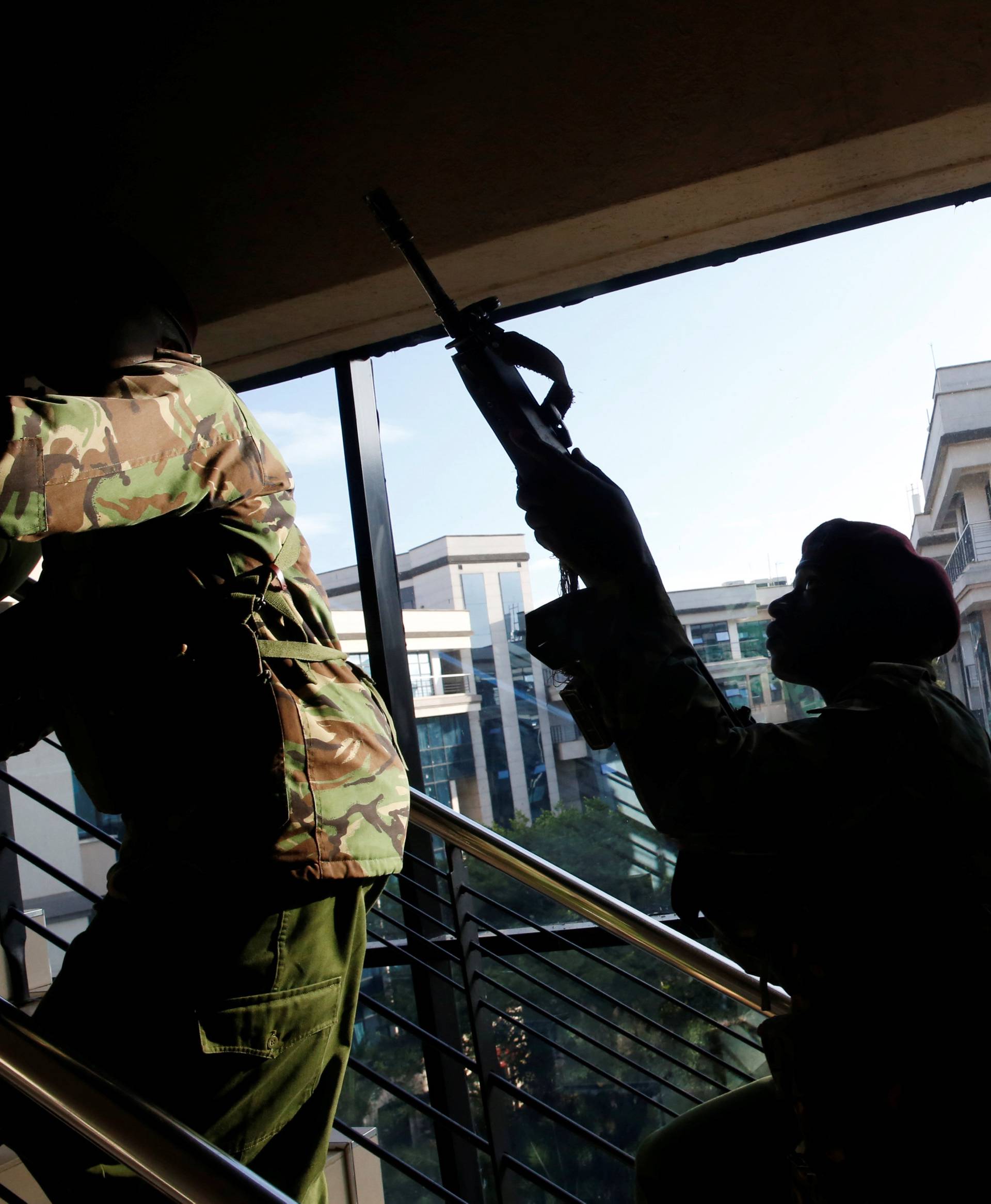 Members of security forces secure a building at the scene where explosions and gunshots were heard at the Dusit hotel seen in the background, in Nairobi