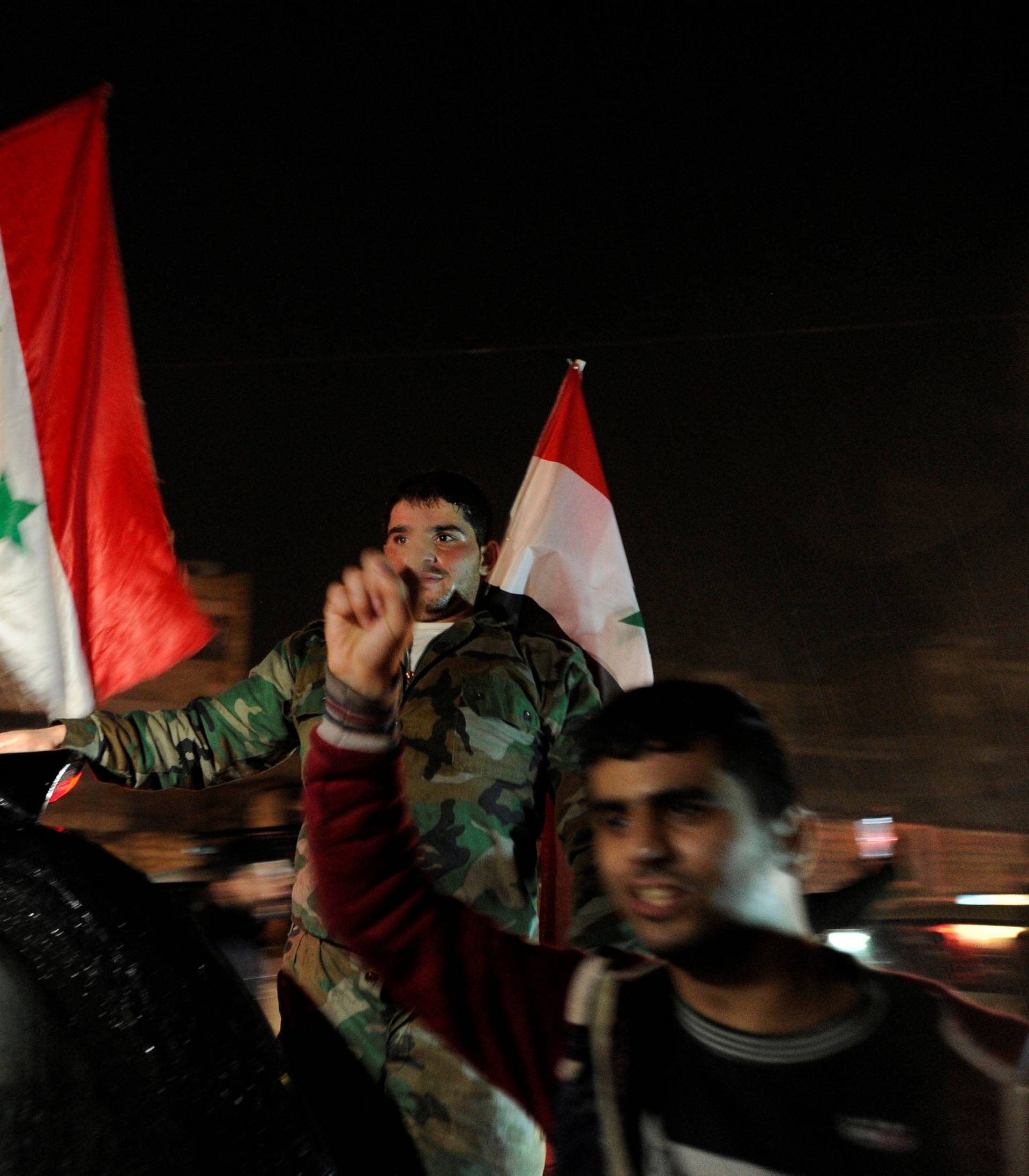 Supporters of Syria's President Bashar al-Assad carry their national flags as they celebrate what they say is the Syrian army's victory against the rebels, in Aleppo