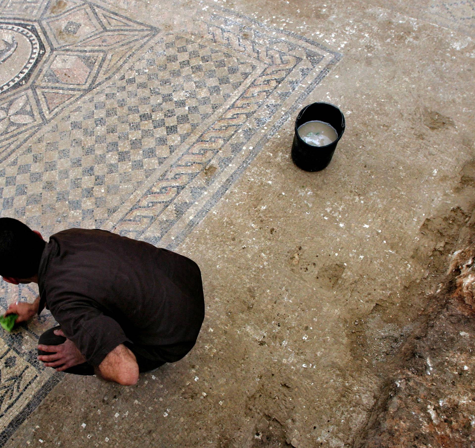 FILE PHOTO: A prison inmate cleans a mosaic on the floor of ancient prayer hall that was discovered on the site of Megiddo Prison in northern Israel