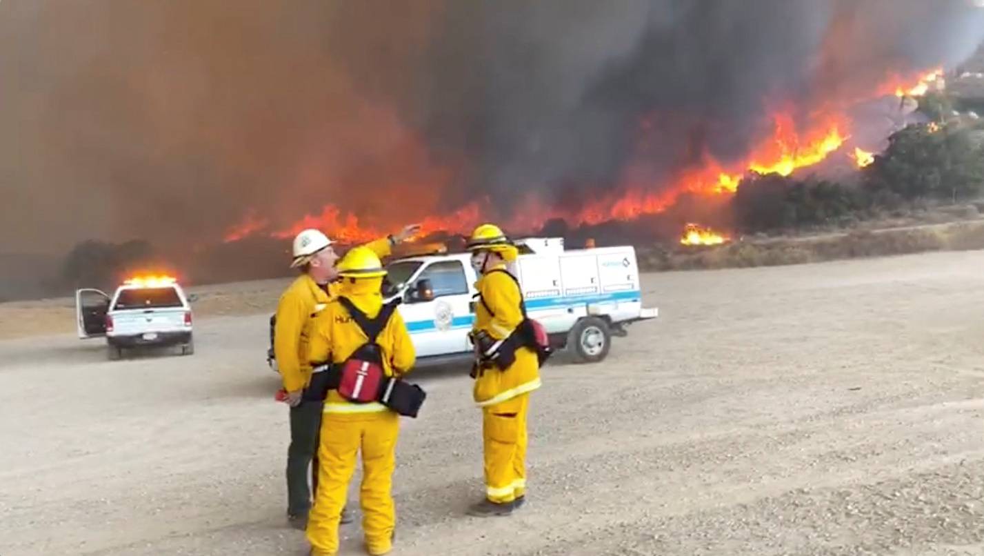 Members of the San Diego Humane Society's Emergency Response Team react as the Valley Fire rages in the background in San Diego, California