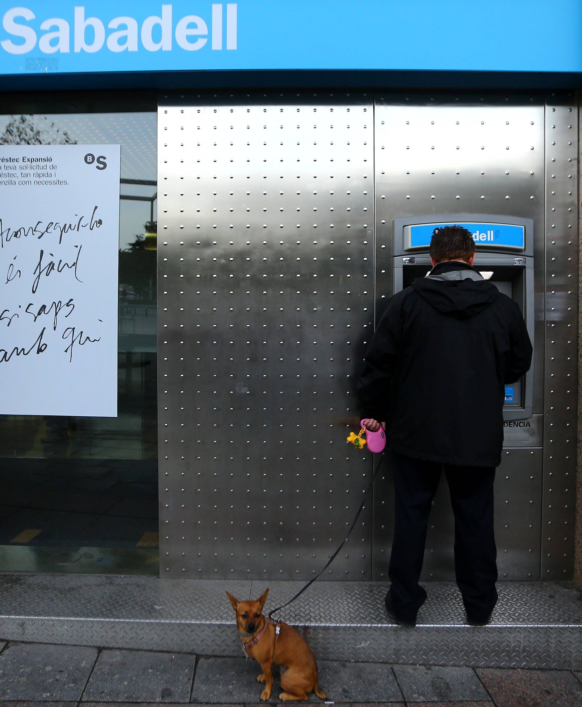 A man uses a Sabadell Bank ATM machine in Barcelona to withdraw money as part of an action to protest the transfer of the bank's headquarters out of Barcelona,