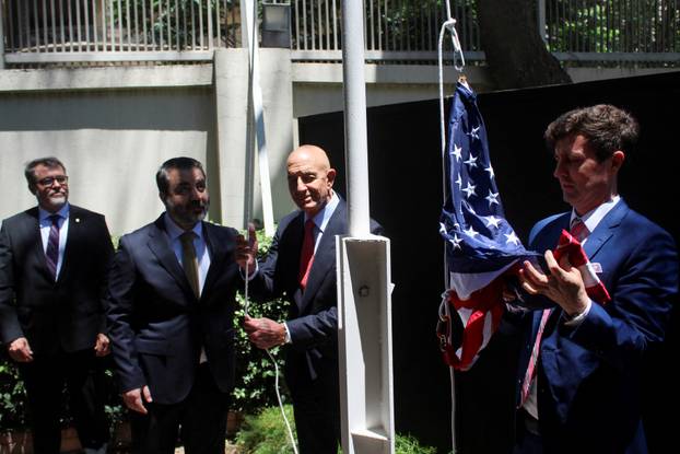 Syrian Foreign Minister Asaad Hassan al-Shibani stands next to U.S. envoy for Syria Thomas Barrack as he raises the American flag at U.S. ambassador's residency in Damascus