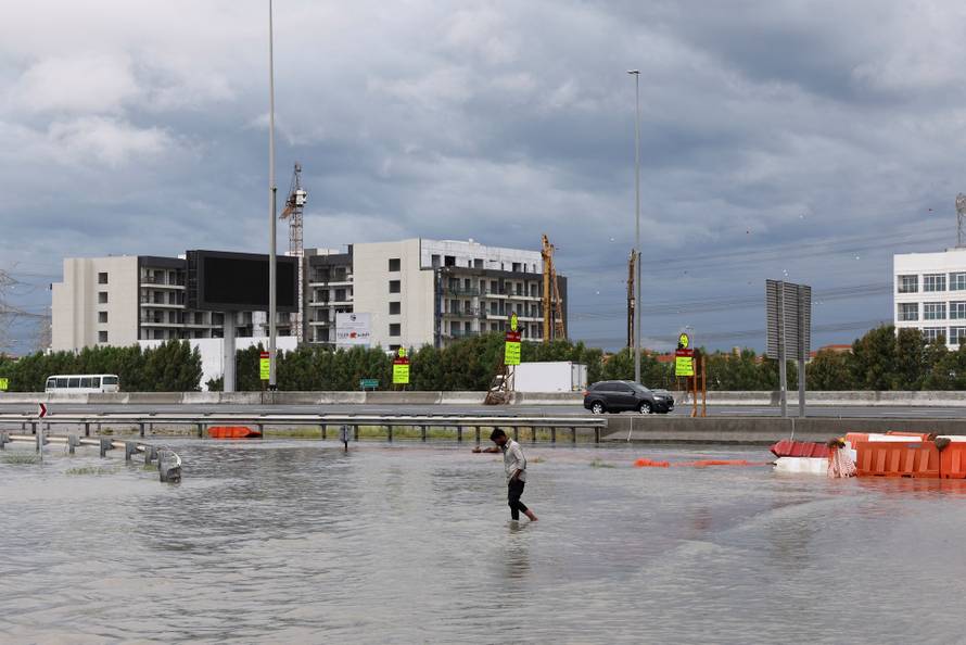 Person walks through water in a flooded street following heavy rains in Dubai
