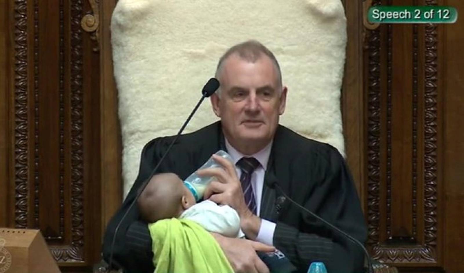 Screenshot from a Parliament broadcast of New Zealand Speaker Trevor Mallard feeding a Member of Parliamentâs baby during a parliamentary session in Wellington