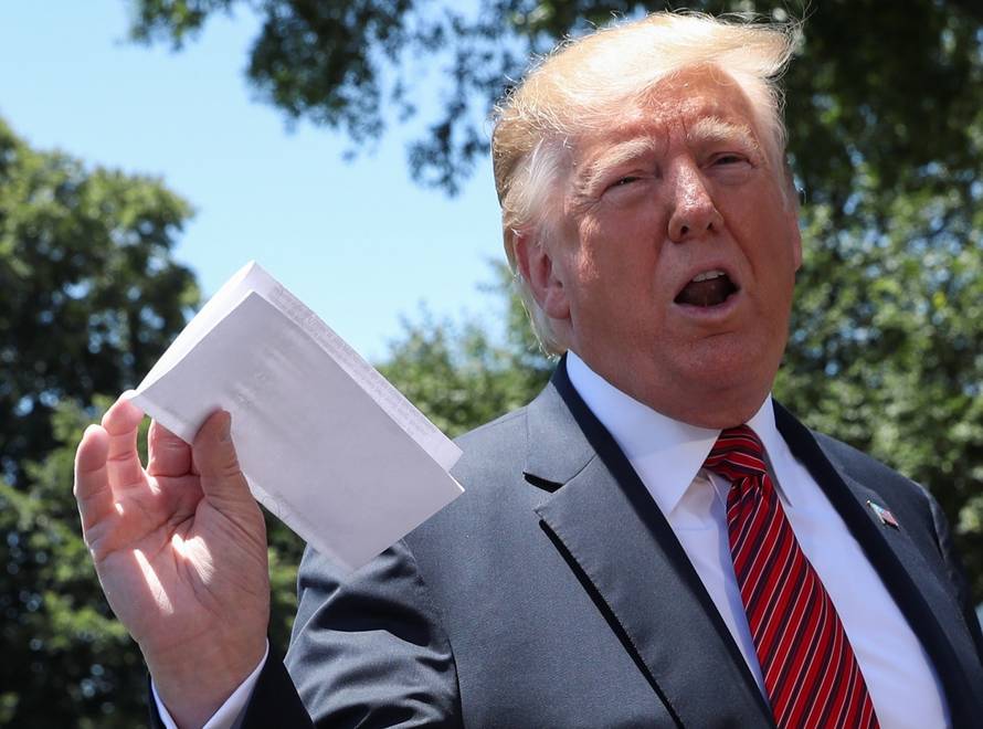 U.S. President Trump holds copy of regional asylum plan as he departs for travel to Iowa from the White House in Washington