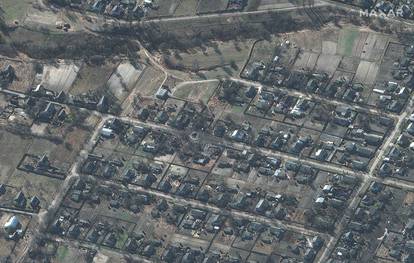 A satellite image shows a large crater in the middle of a residential area and destroyed homes, in Sukachi village, north of Kyiv