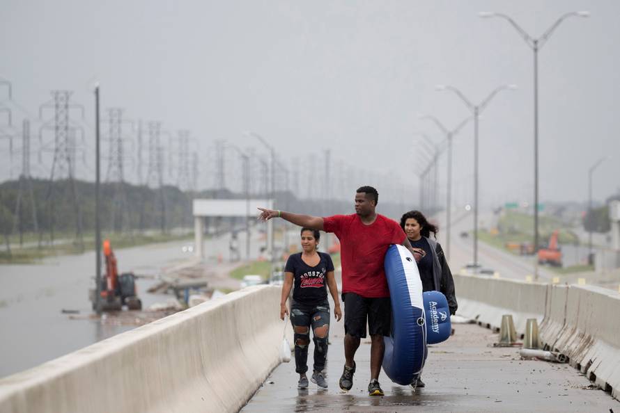Jeremy Collier points toward a flooded shopping center after rescuing his wife Anna Collier and friend Melissa Merito from flood waters in Pearland, in the outskirts of Houston