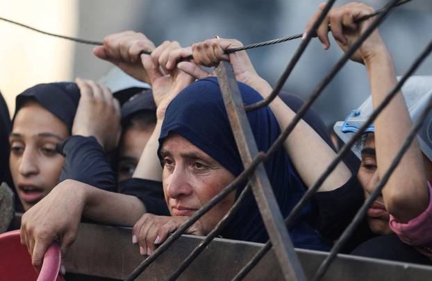 Palestinians wait to receive food from a charity kitchen, amid a hunger crisis, in Gaza City