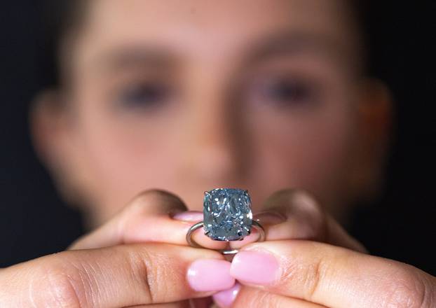 A Sotheby’s staff wears "The Mediterranean Blue" diamond during an auction preview in Geneva