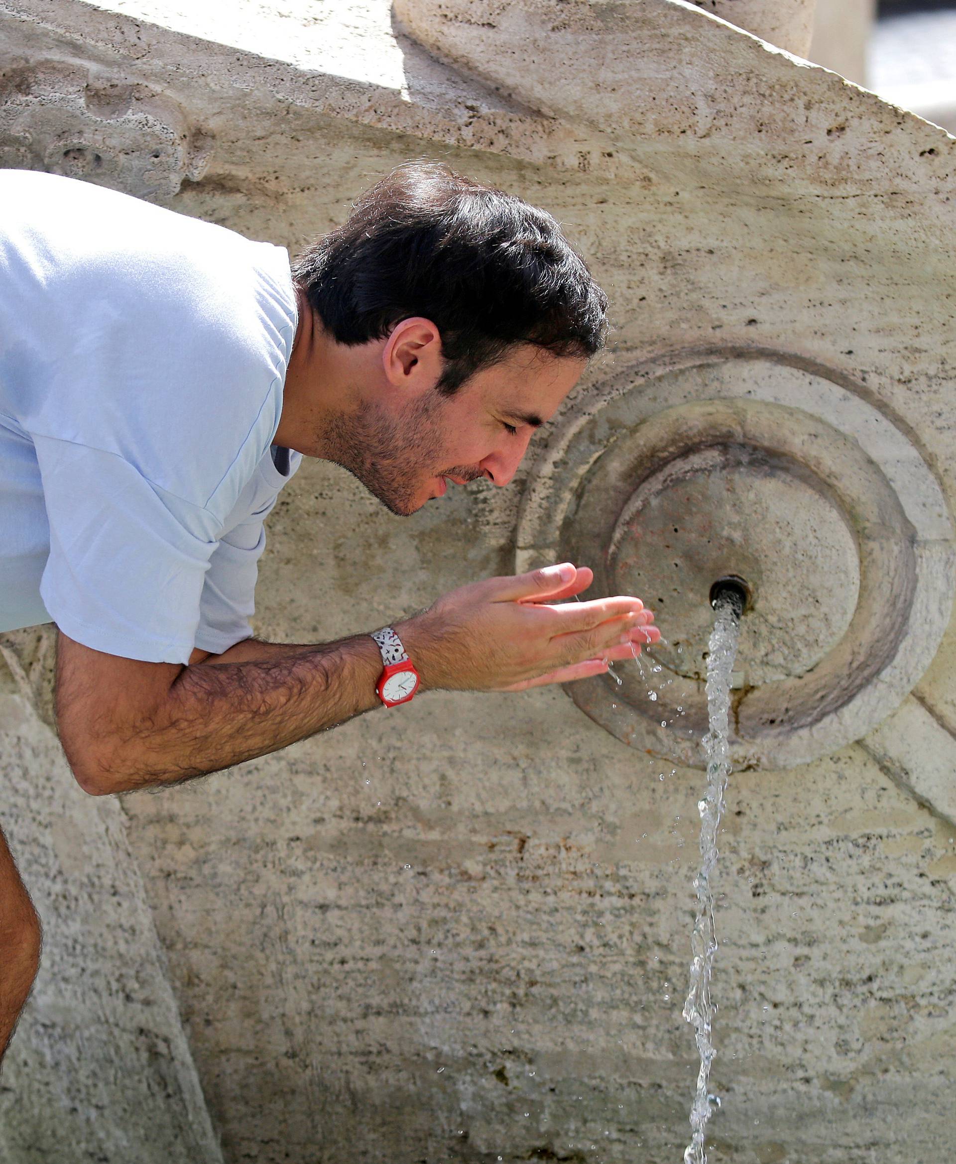 FILE PHOTO: A man cools off by a fountain in downtown Rome as a heatwave hits Italy
